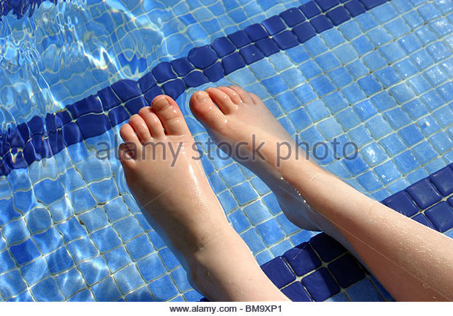 a-young-child-dipping-her-feet-into-a-swimming-pool-bm9xp1.jpg